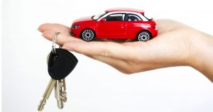 hand holding a red toy car and car keys