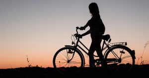 a woman and bike silhouetted in a sunset 