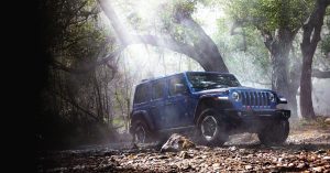 Blue 2020 Jeep Wrangler off roading in a wooded area
