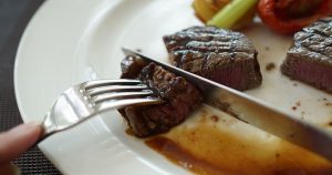 A steak being cut on a white plate