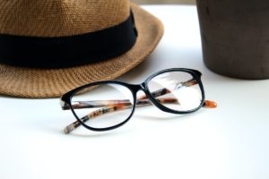 Black glasses with grown tortoise accents | Brown hat in background with black band on white table